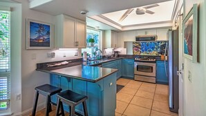 Eine Küche mit einer zentralen Kochinsel, blauen Schränken, einem großen Aquarium und einem Deckenventilator.