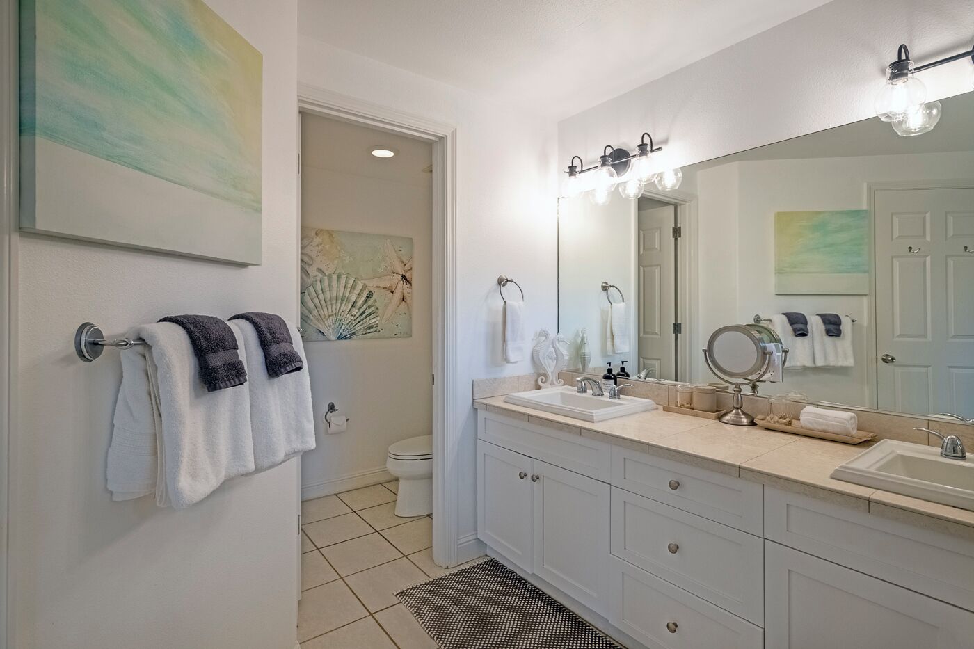 A modern bathroom with two sinks, a large mirror, and a shower area.