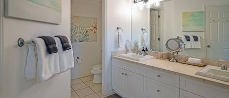 A modern bathroom with two sinks, a large mirror, and a shower area.
