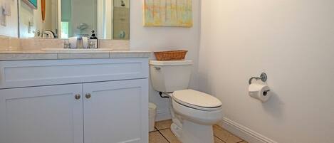 A bathroom with a white vanity, a toilet, and a wall-mounted sink.
