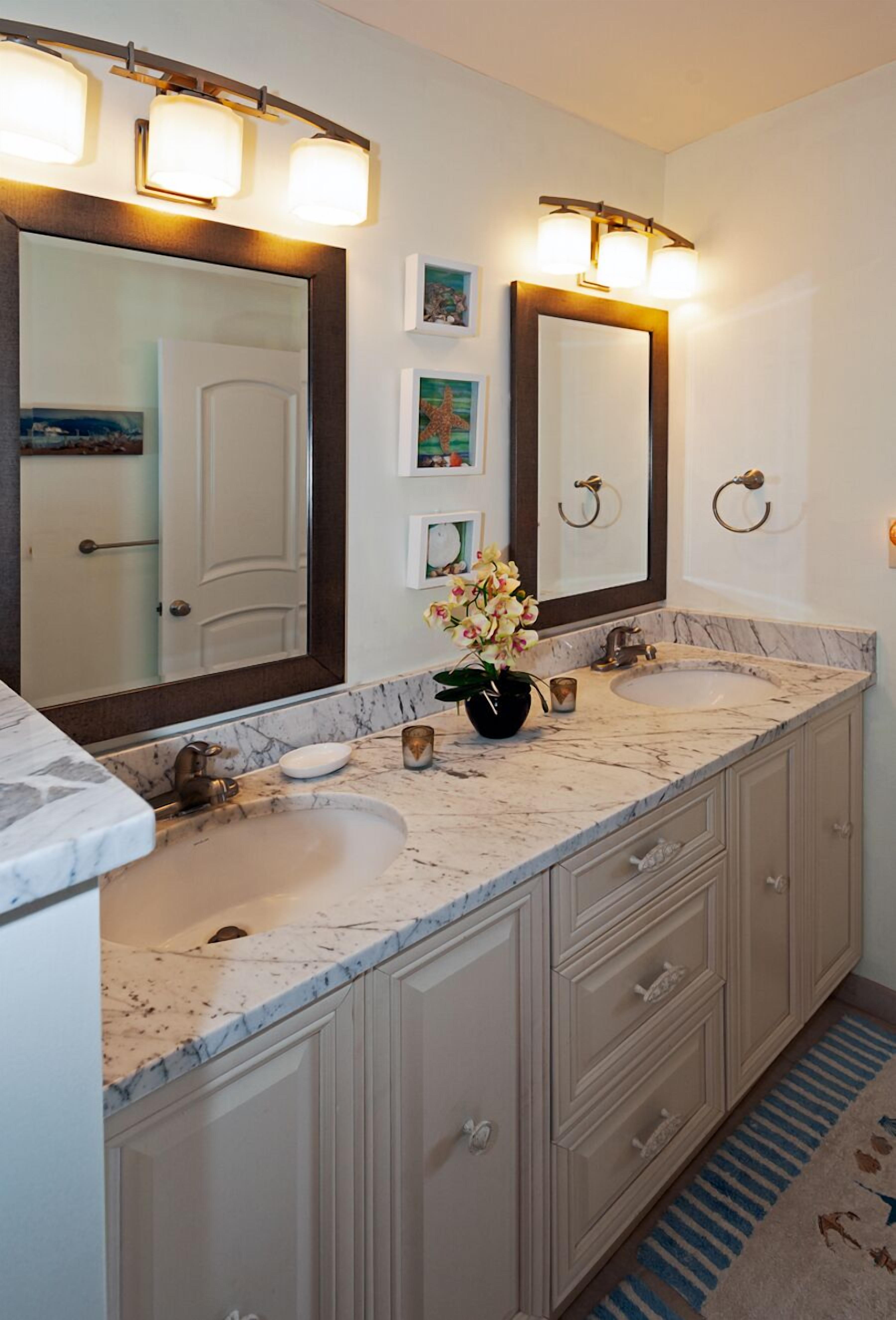 A bathroom with two sinks, a large mirror, and wall-mounted lights.