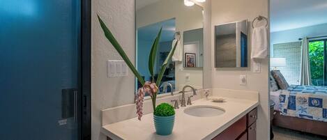Un baño con un lavamanos blanco, un espejo y una planta en maceta.