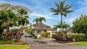 Zona residencial con una casa grande, palmeras y un letrero que dice "Kahala at Poipu Kai".