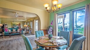 Un salón amplio con comedor, ventanas grandes y vistas a palmeras.