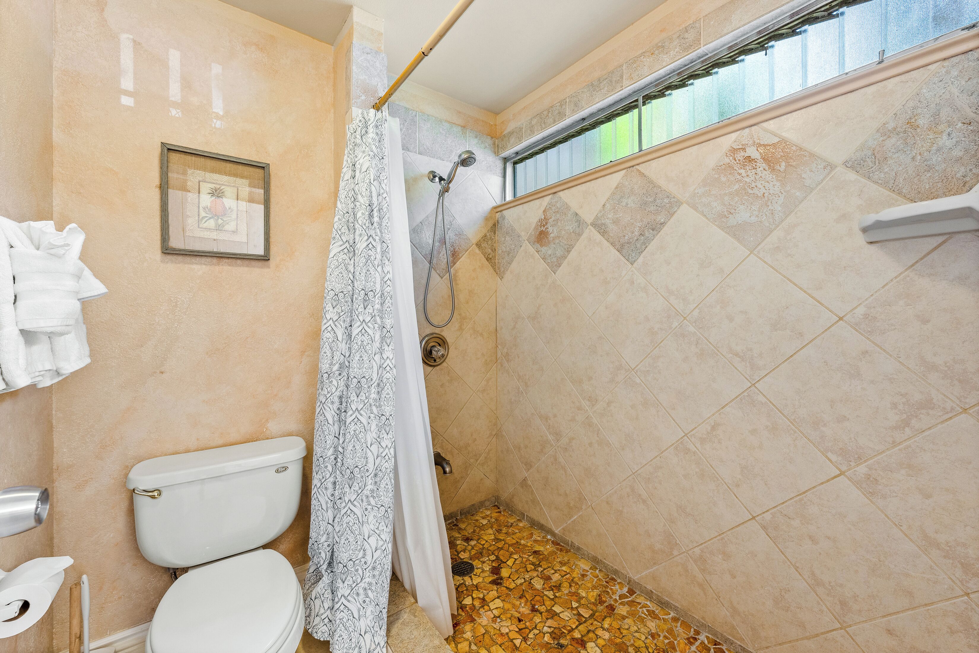 Un baño con ducha, inodoro y un cuadro en la pared.