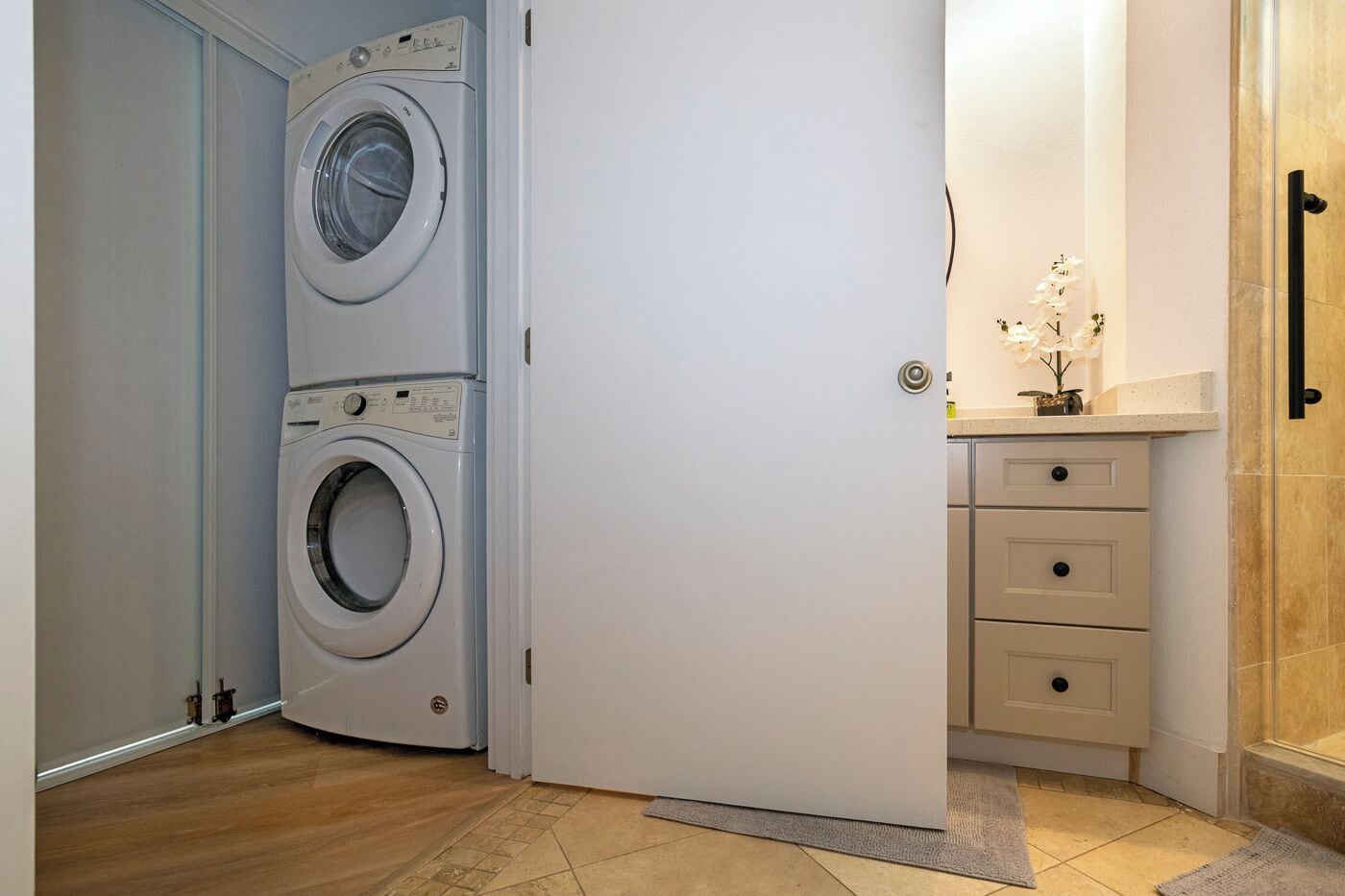 Un lavadero con dos lavadoras apiladas y un mueble bajo con cajones.