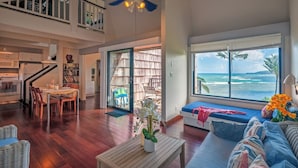 A spacious living area with a view of the ocean, a dining area, and a kitchen. - Sealodge E6 (Princeville)