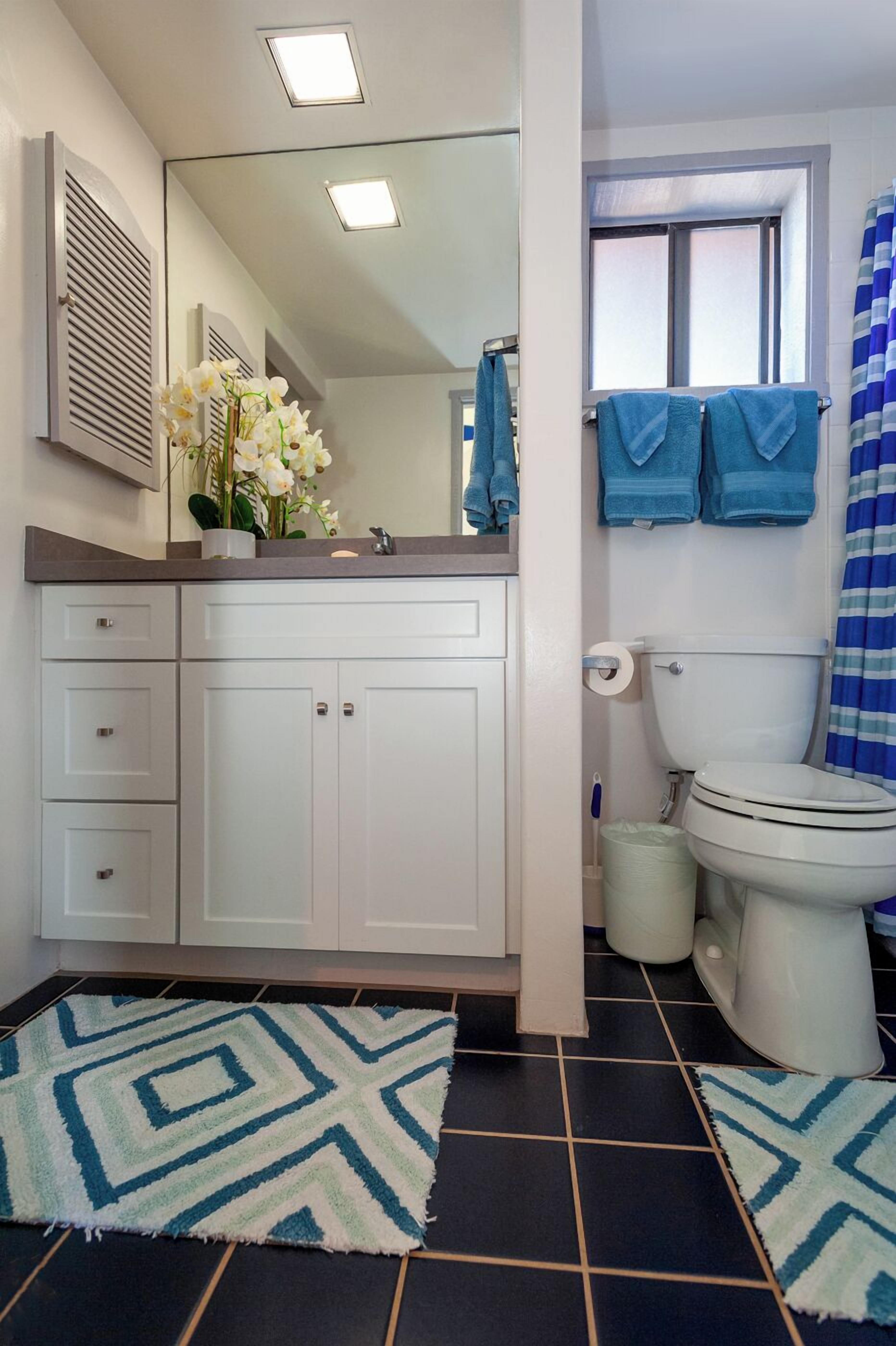 Een badkamer met een wit wastafelmeubel, toilet en douchehoek.