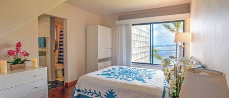 Un dormitorio con una cama grande, una ventana con vistas, un aparador blanco y una mesita de noche con lámpara.