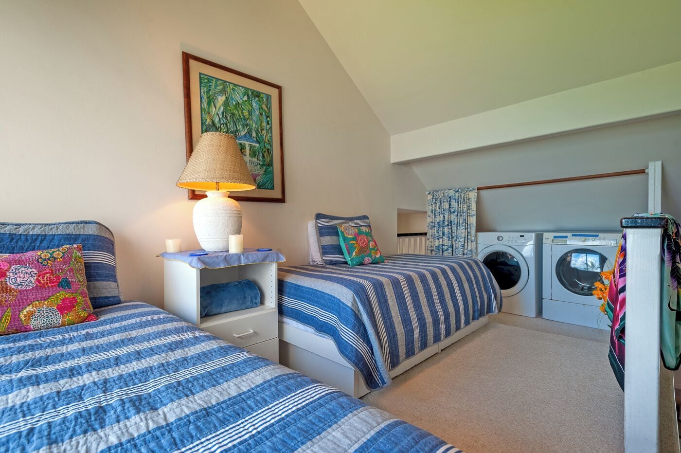 A bedroom with two beds, a washing machine, and a laundry area.