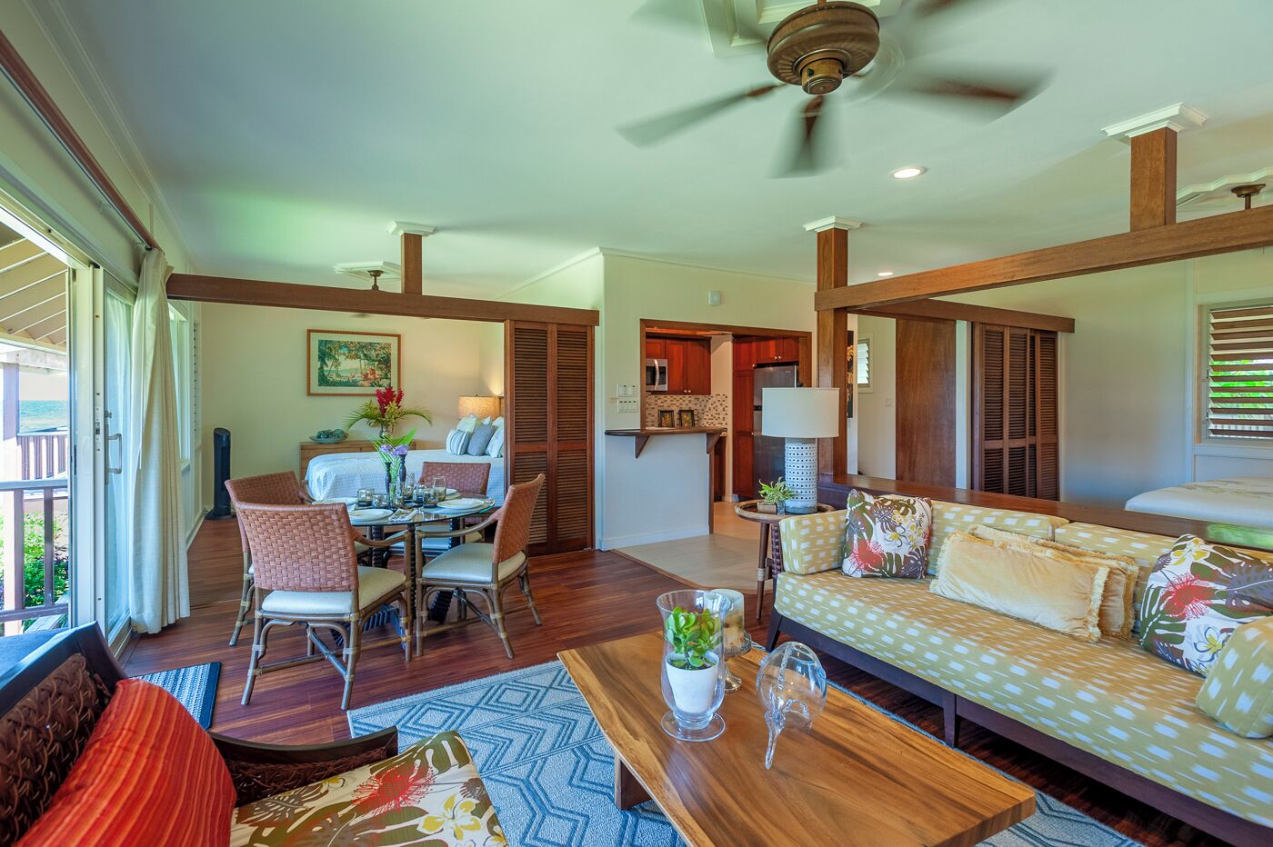 A spacious living area with a dining table, chairs, a sofa, and a ceiling fan.