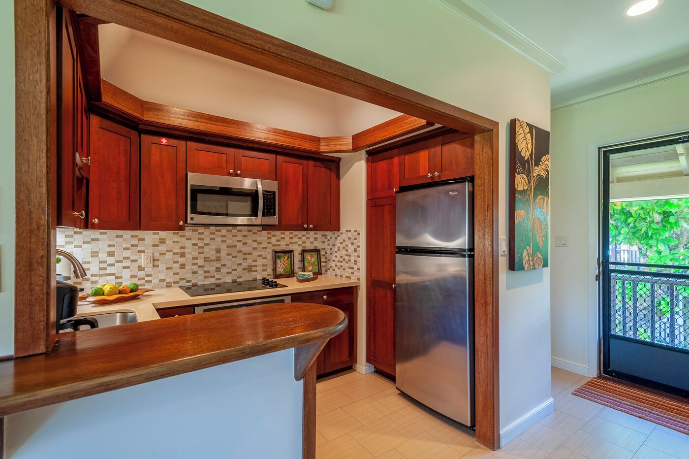 A kitchen with wooden cabinets, a stainless steel refrigerator, and a microwave.