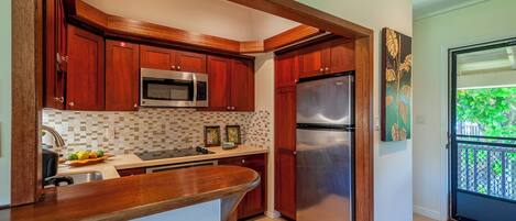 A kitchen with wooden cabinets, a stainless steel refrigerator, and a microwave.