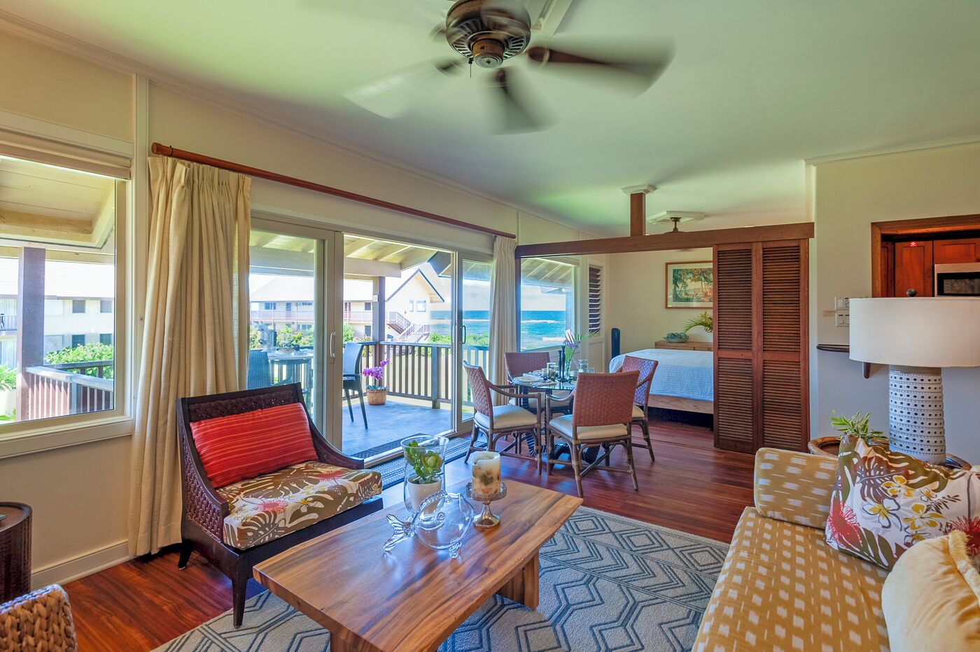 A spacious living area with a balcony, a dining table, and a sofa.