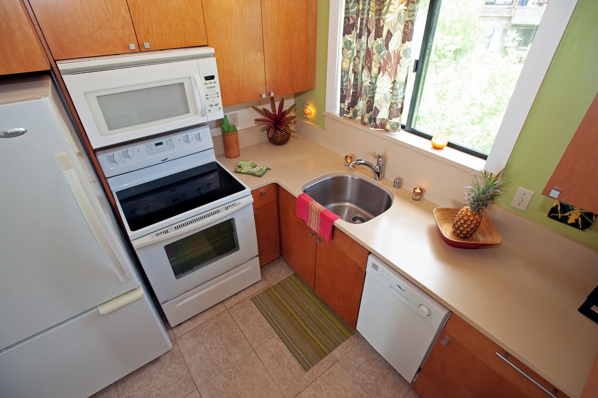 A compact kitchen with a microwave, oven, sink, and dishwasher.