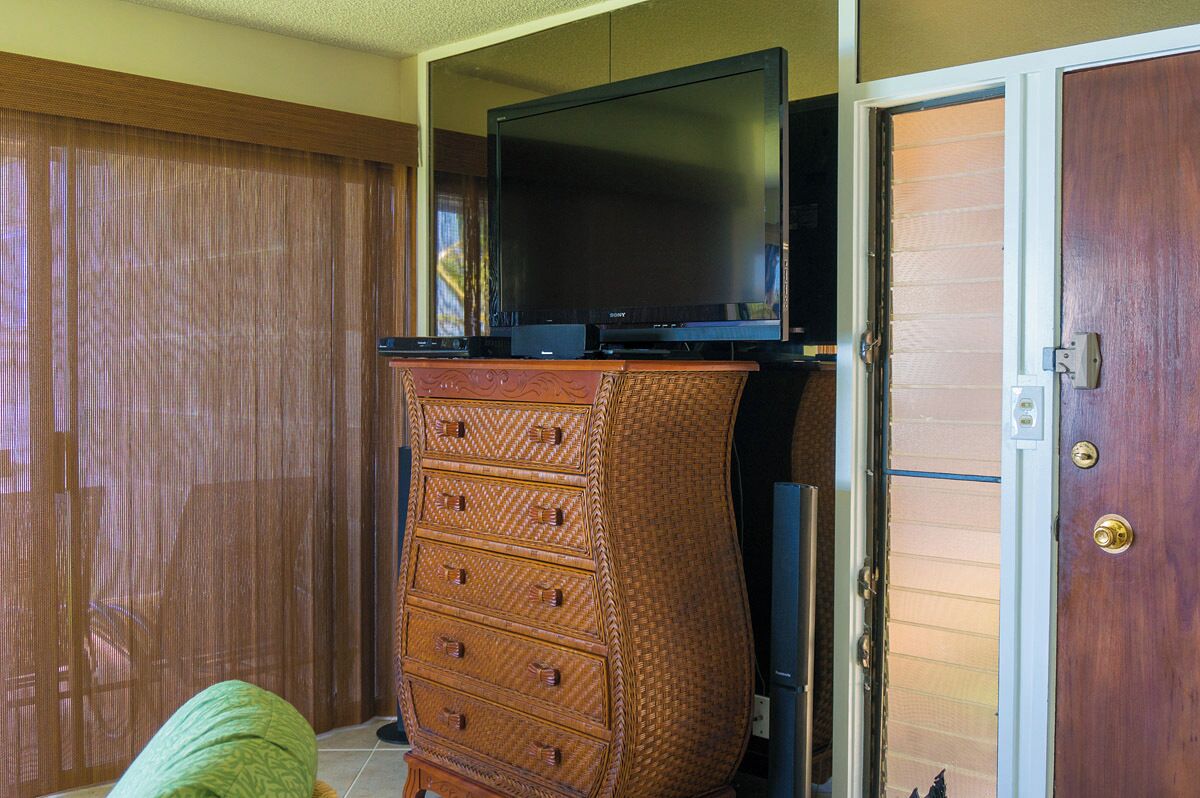 Une pièce avec un téléviseur posé sur une commode en bois, une porte coulissante et une armoire en bois.
