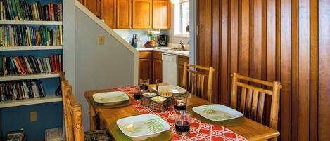 Comedor con una mesa de madera dispuesta para cuatro personas, rodeado de estanterías llenas de libros.