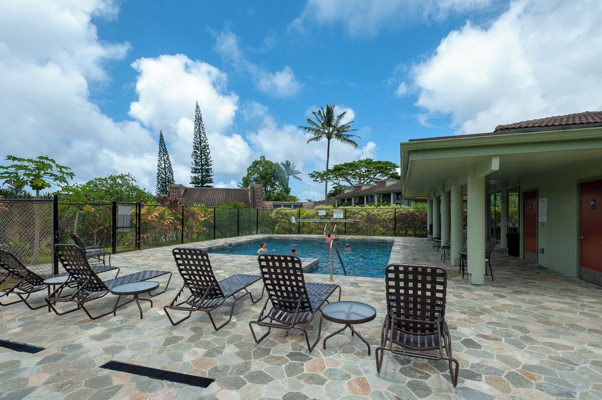 A pool area with lounge chairs and a covered seating area.