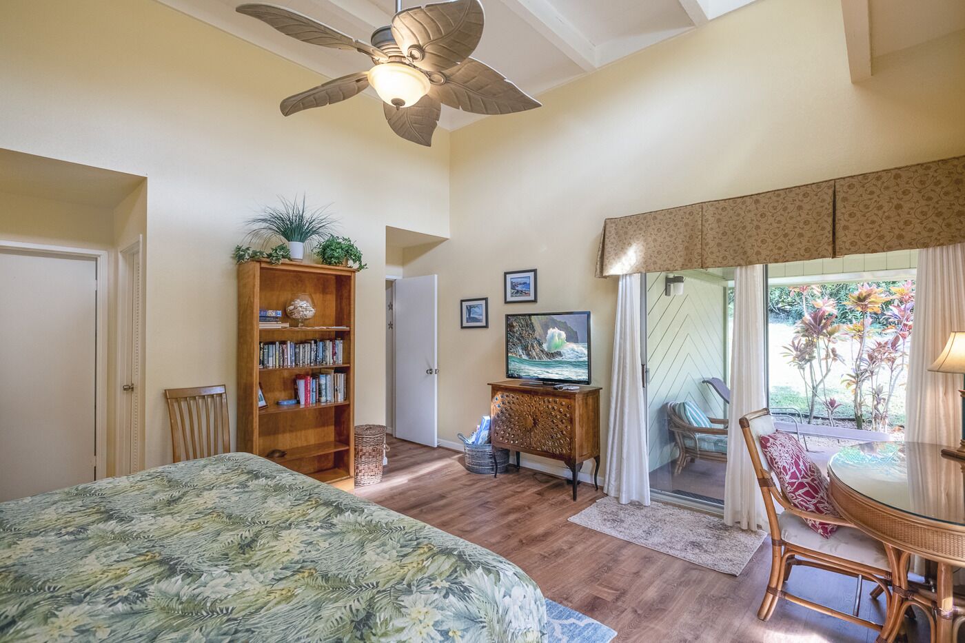 Une chambre spacieuse avec un grand lit, une biblioth èque en bois, une télévision et un coin repas comprenant une table et des chaises.