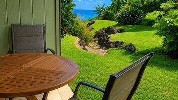 A wooden table and chairs in a garden with a view of the ocean.