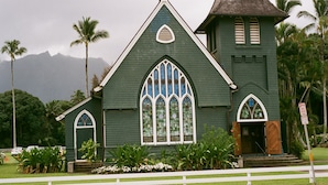 A green church with a steeple, large arched windows, and a bell tower. - Paniolo 210b (Princeville)