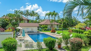 A swimming pool surrounded by lush greenery, palm trees, and a well-maintained lawn. - Paniolo 210b (Princeville)