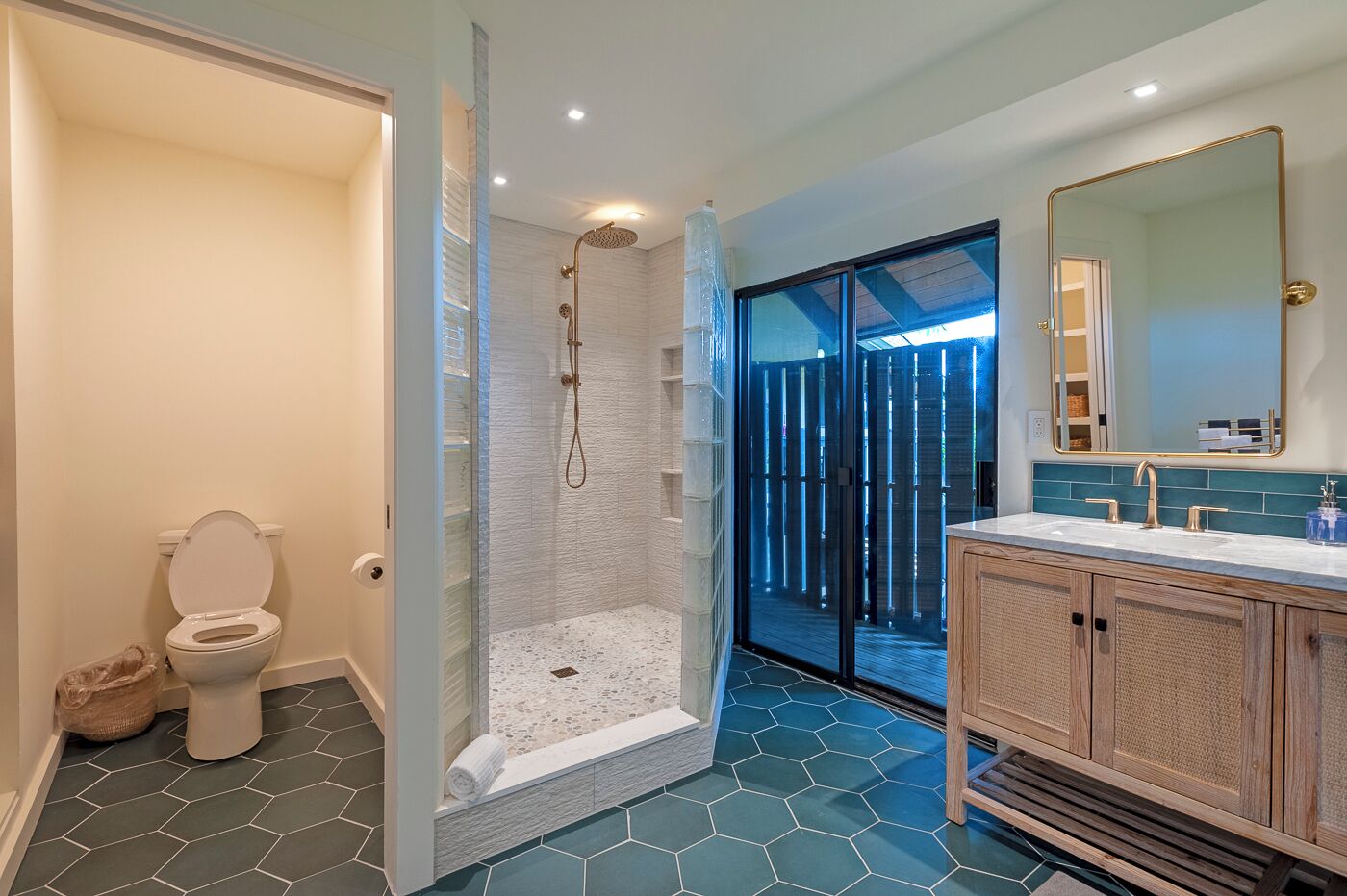 Une salle de bain moderne avec une douche à parois de verre, des toilettes et un meuble-lavabo avec un miroir.
