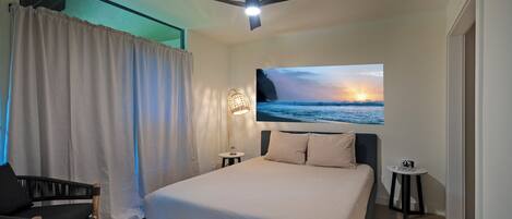 A modern bedroom with a bed, a ceiling fan, a nightstand, a chair, and a wall-mounted lamp.