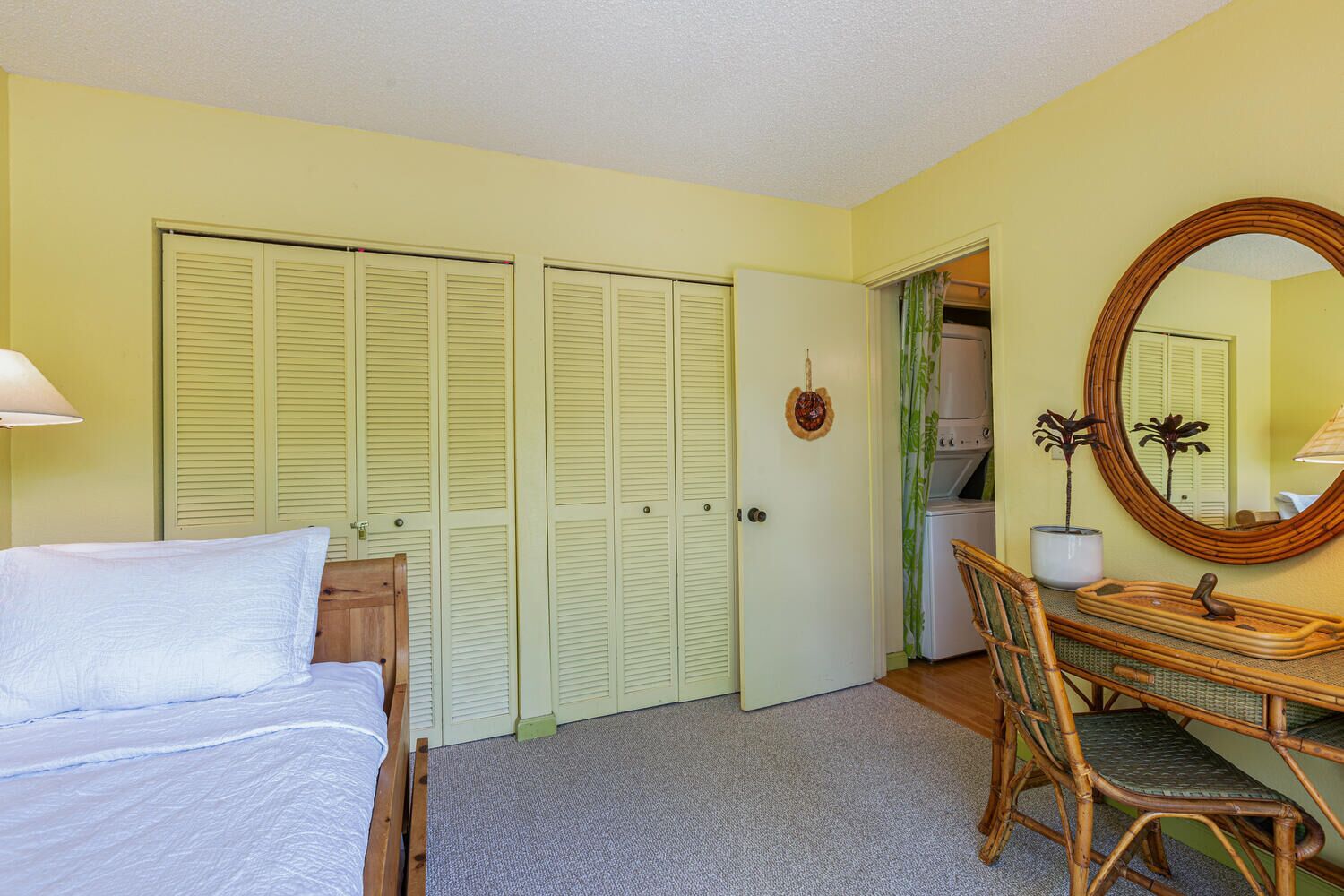 A bedroom with a bed, a desk with a chair, a mirror, and a wardrobe with louvered doors.