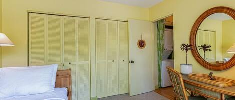 A bedroom with a bed, a desk with a chair, a mirror, and a wardrobe with louvered doors.