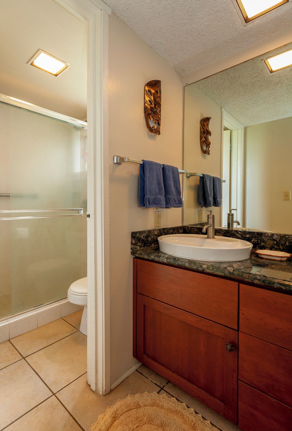 A bathroom with a glass shower enclosure, a white sink, and a wooden vanity.