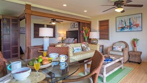 A cozy living room with a glass dining table, wicker furniture, and a ceiling fan. - Hanalei Colony Resort I-2 (Hanalei)
