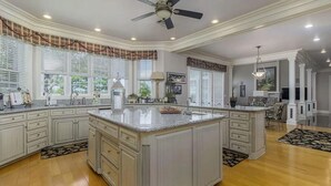 Una cocina amplia con una isla grande, armarios blancos y piso de madera.