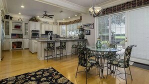 Una cocina amplia con una isla central, taburetes de bar y una mesa de comedor con sillas.