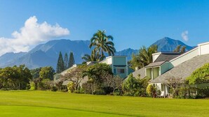 A resort with multiple buildings, a well-maintained lawn, and a mountain backdrop. - Kamahana 24 (Princeville)