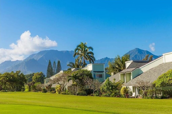 A resort with multiple buildings, a well-maintained lawn, and a mountain backdrop.