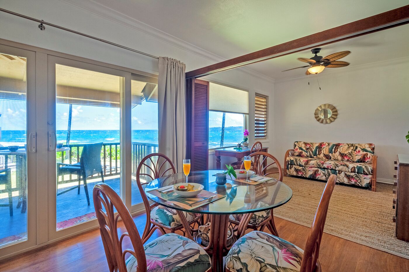A dining area with a glass table, chairs, and a view of the ocean.