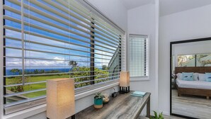 Ein modernes Schlafzimmer mit einem hölzernen Bett, Meerblick und einem Balkon mit großen Fenstern.