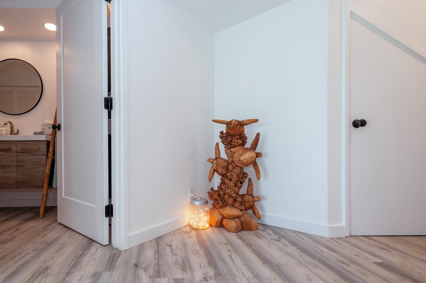 A corner of a room with a white door, a wooden floor, and a decorative sculpture of a turtle.