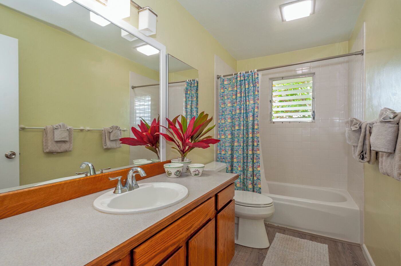 A bathroom with a sink, mirror, toilet, and shower.