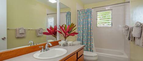 A bathroom with a sink, mirror, toilet, and shower.