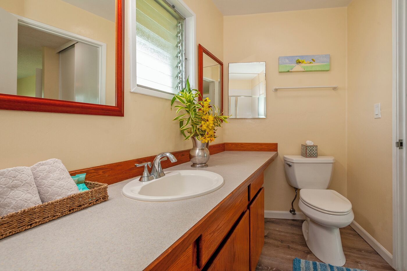 A bathroom with a double sink vanity, a toilet, and a window with blinds.
