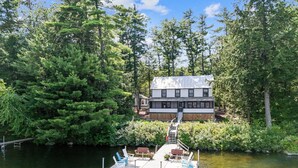 A lakeside cabin with a dock, surrounded by dense forest.