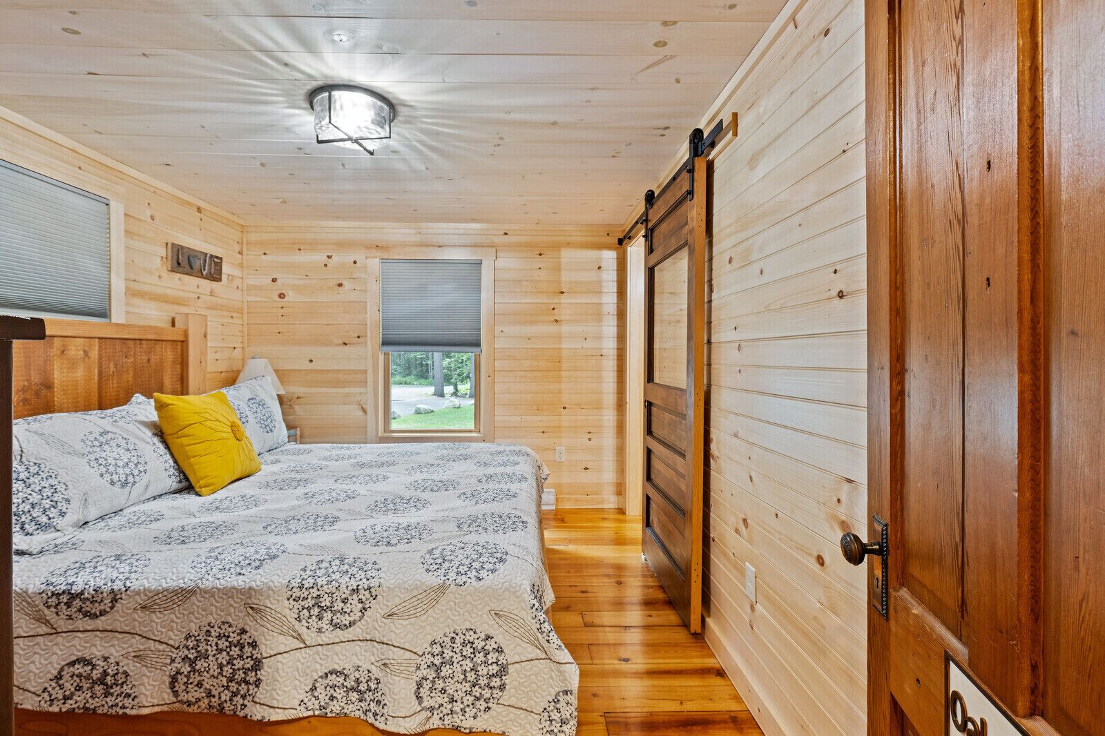 Ein Schlafzimmer einer Holzhütte mit einem Bett, einem Fenster und einer Tür.