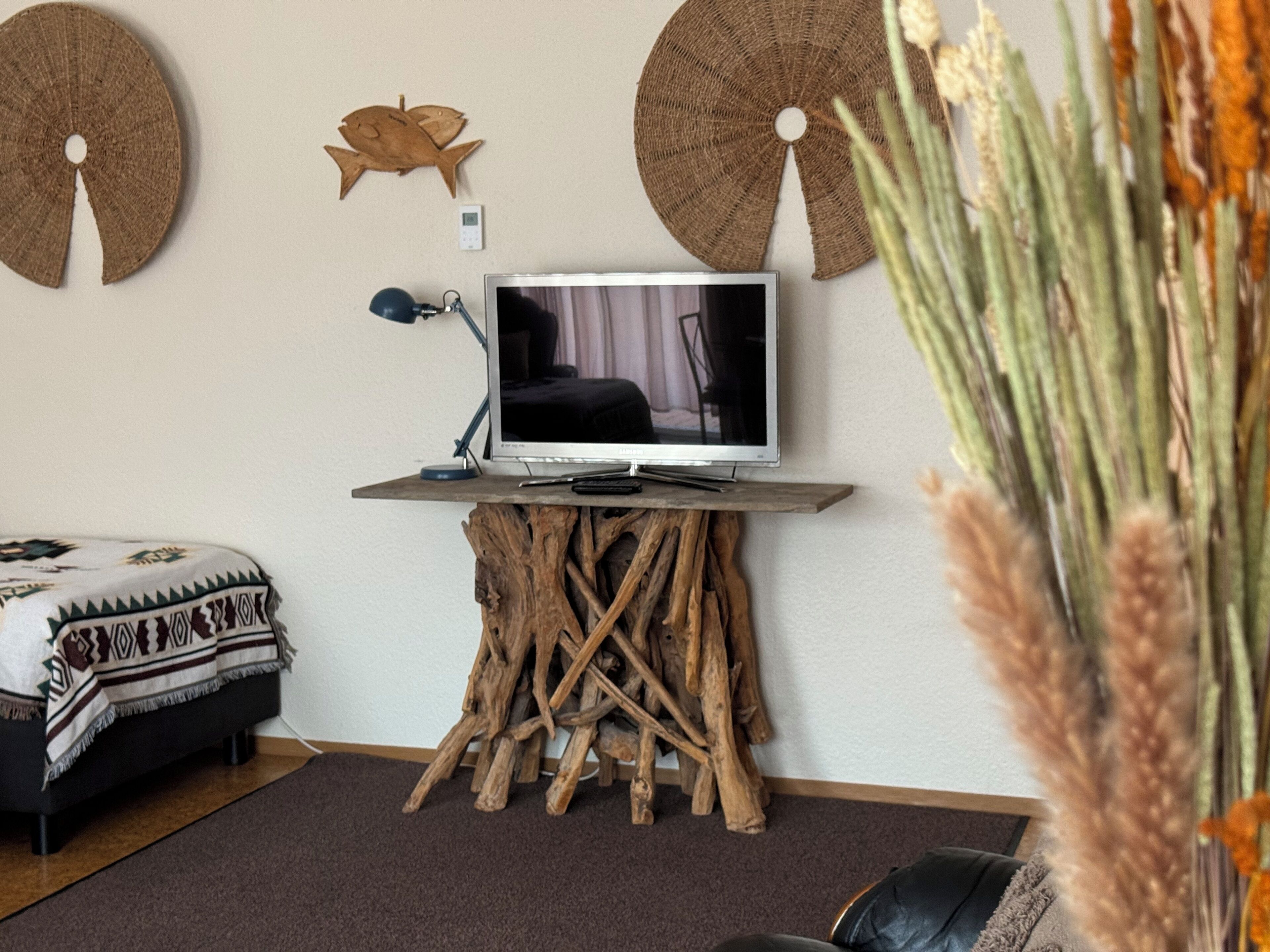 A modern living room with a television on a wooden stand, a sofa, and decorative wall art.