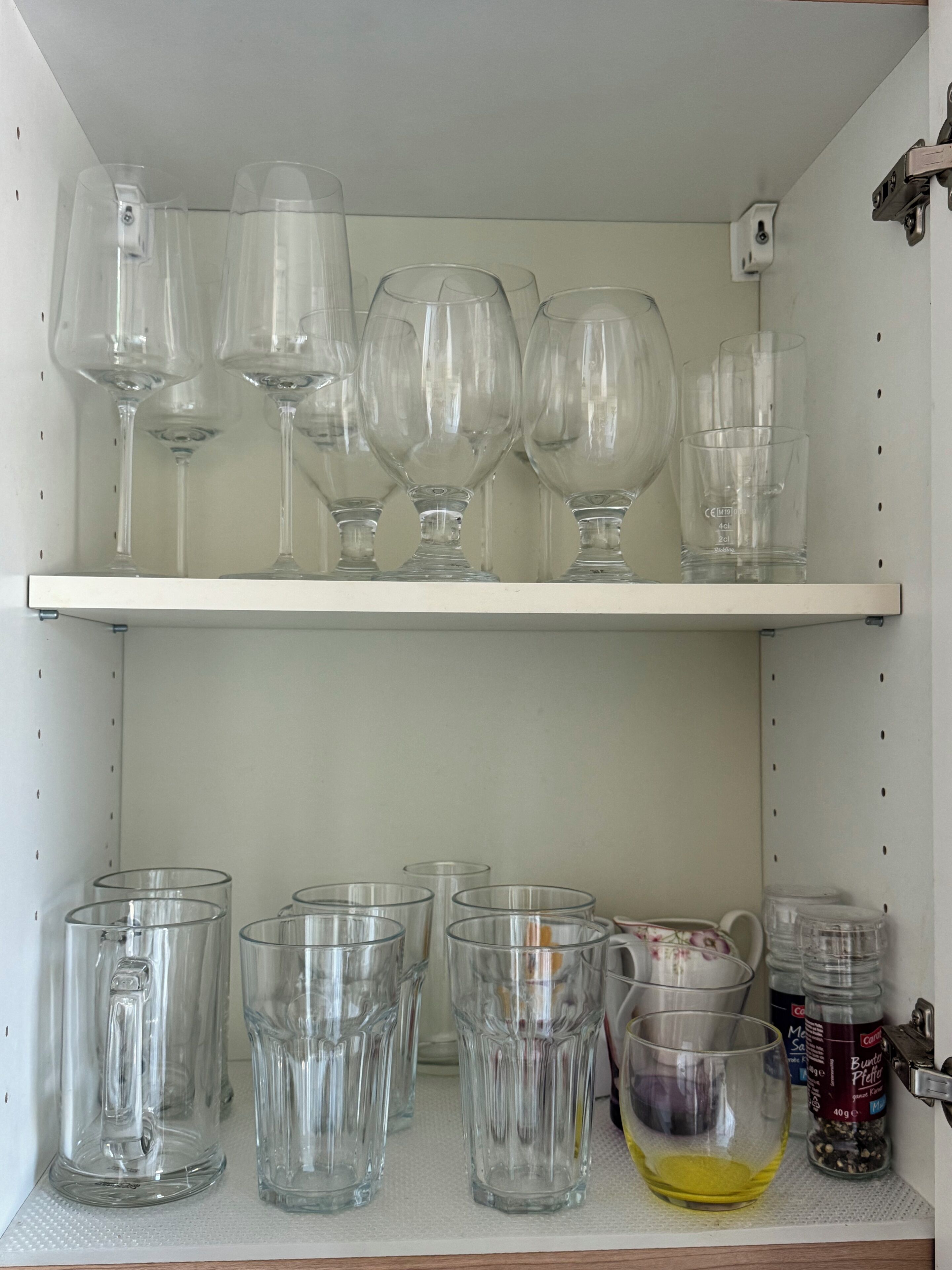 A shelf with various glassware including wine glasses and tumblers.