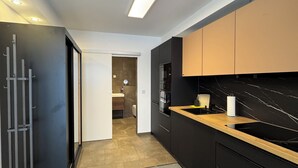 Een moderne keuken met zwarte kastjes, een houten aanrechtblad en een zwarte spoelbak.