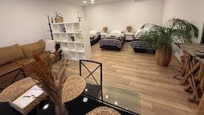 Een moderne woonkamer met een bank, twee bedden, een glazen salontafel en een wit wandrek.