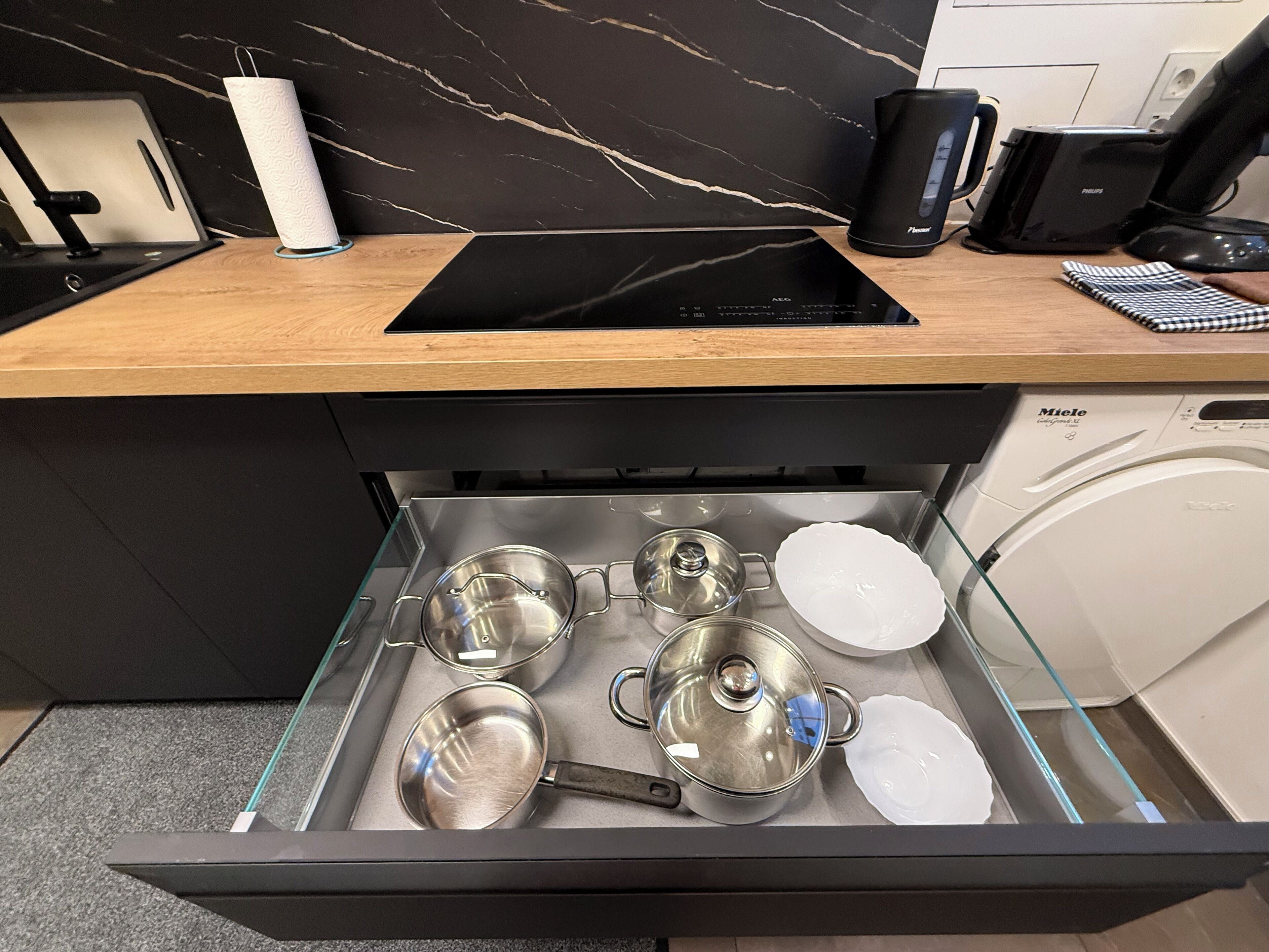 Une cuisine dotée d’un plan de travail noir, d’une machine à café, d’un grille-pain et d’un lave-vaisselle.