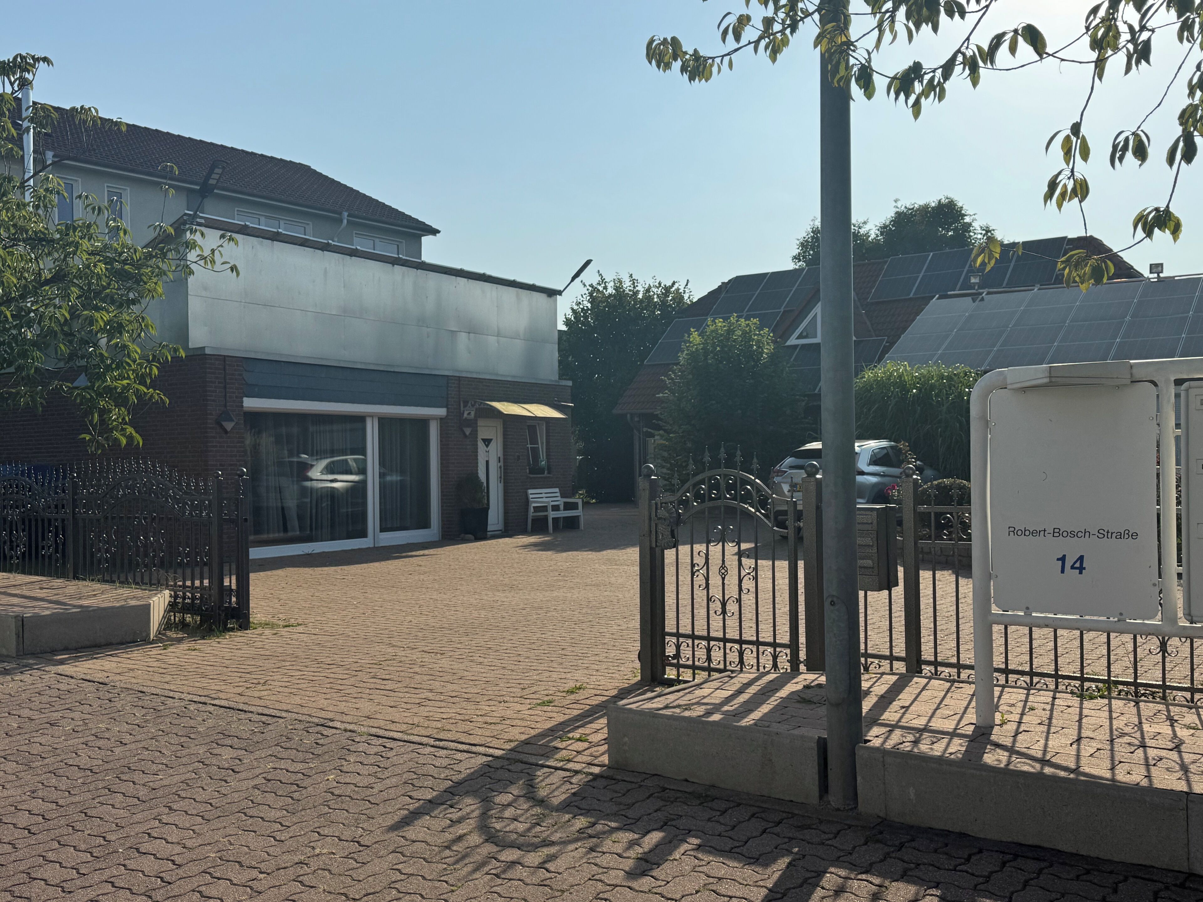A building with a paved entrance, a gated driveway, and a mailbox labeled "Robert-Bosch-Straße 14".